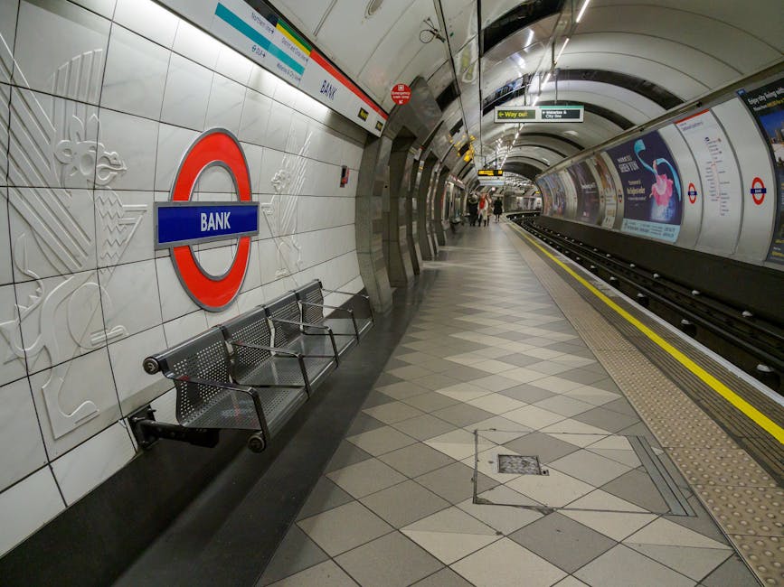 The interior of a modern train carriage showing clean, smooth surfaces with beige and grey plastic seats arranged along both sides facing inward, separated by a central aisle with a speckled grey floo